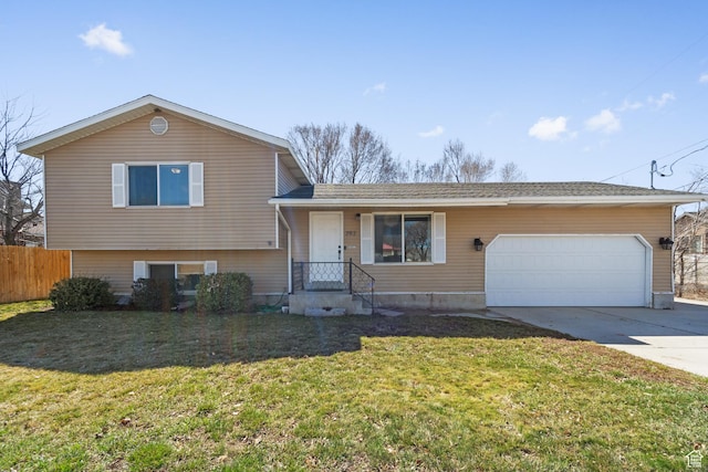 tri-level home featuring a garage, fence, concrete driveway, and a front yard