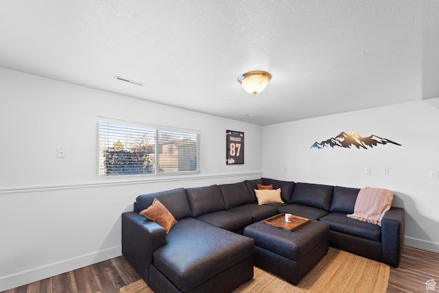 living room featuring baseboards, a textured ceiling, visible vents, and wood finished floors
