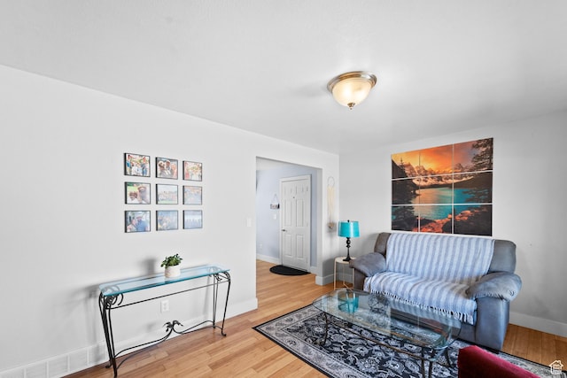 living room with baseboards, visible vents, and wood finished floors