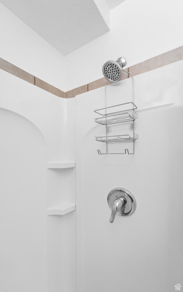 interior details featuring a shower and a textured ceiling
