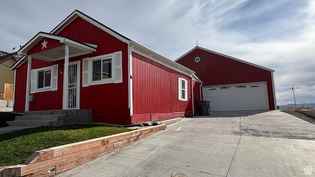view of front facade with entry steps, an outbuilding, and concrete driveway