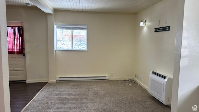 spare room featuring a baseboard heating unit, dark wood finished floors, crown molding, and baseboards