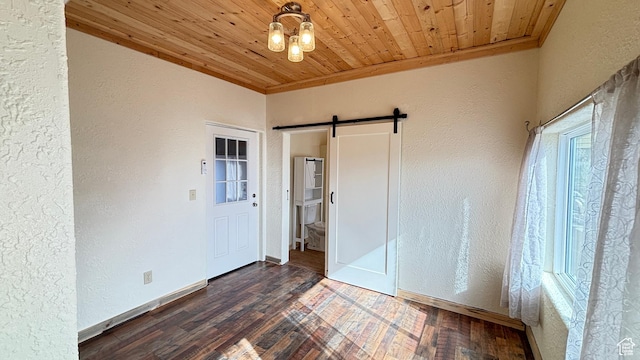 interior space with a textured wall, wooden ceiling, wood finished floors, and a barn door