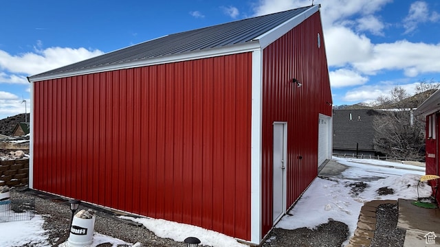 snow covered structure featuring an outdoor structure and an outbuilding
