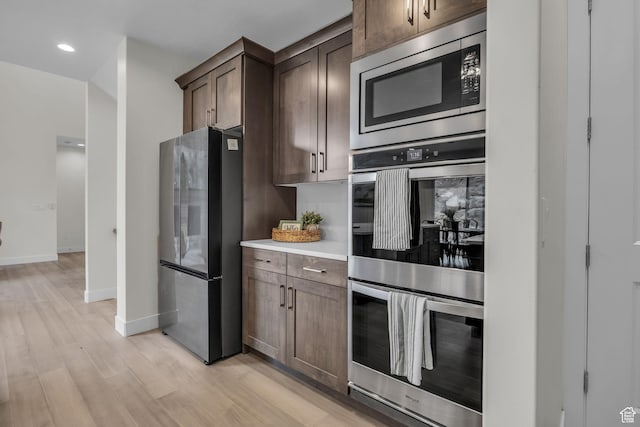 6579 W Bonnie Jean Ln Unit 12, Herriman, UT 84096 - kitchen with light countertops, dark brown cabinetry, light wood-type flooring, stainless steel appliances, and baseboards