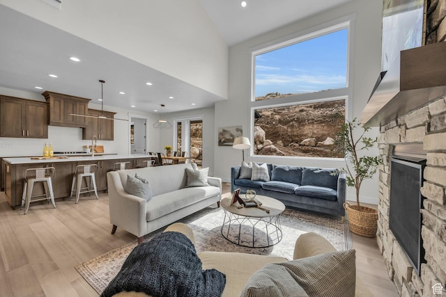 6579 W Bonnie Jean Ln Unit 12, Herriman, UT 84096 - living area featuring baseboards, a fireplace, a towering ceiling, recessed lighting, and light wood-type flooring