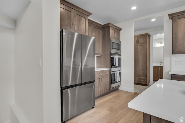 6579 W Bonnie Jean Ln Unit 12, Herriman, UT 84096 - kitchen featuring light countertops, recessed lighting, appliances with stainless steel finishes, dark brown cabinetry, and light wood-style floors