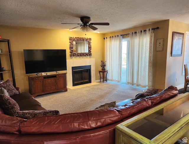carpeted living area with a textured ceiling, a tile fireplace, and a ceiling fan
