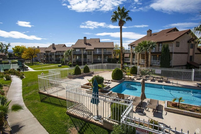 community pool featuring a residential view, a yard, fence, and a patio area