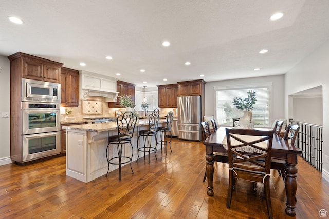 4721 W Country Club Dr, Highland, UT 84003 - kitchen featuring tasteful backsplash, dark wood-type flooring, appliances with stainless steel finishes, light stone counters, and a center island