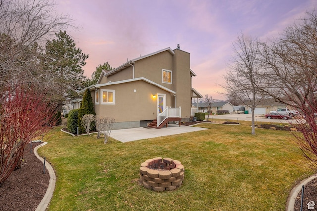 4721 W Country Club Dr, Highland, UT 84003 - back of property at dusk featuring a lawn, an outdoor fire pit, stucco siding, and a patio