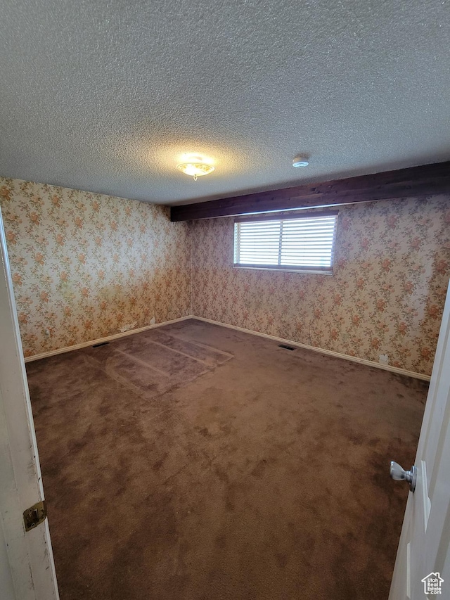 unfurnished room featuring a textured ceiling, wallpapered walls, and carpet floors