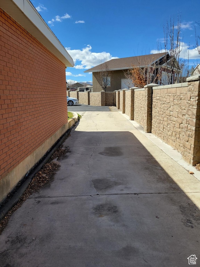 view of side of property with brick siding, fence, and driveway