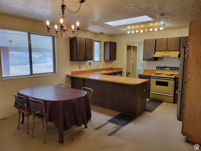 kitchen featuring a peninsula, a skylight, under cabinet range hood, a sink, and electric stove