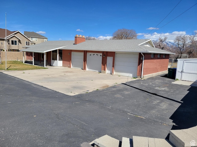 view of front facade with fence, brick siding, driveway, and a chimney