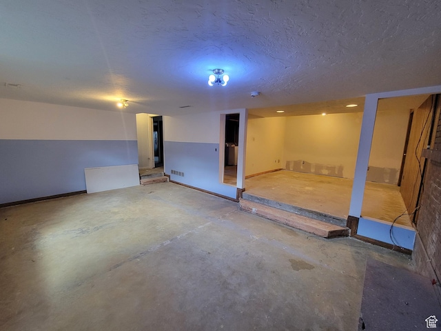finished below grade area featuring visible vents and a textured ceiling