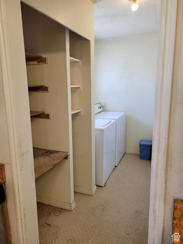 clothes washing area with baseboards, washer and dryer, and laundry area