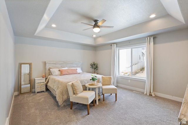 bedroom with light carpet, baseboards, a textured ceiling, and a raised ceiling