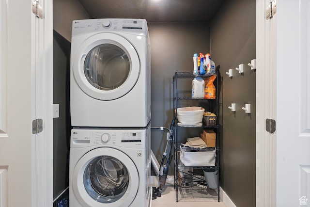 clothes washing area featuring stacked washer and dryer, baseboards, and laundry area
