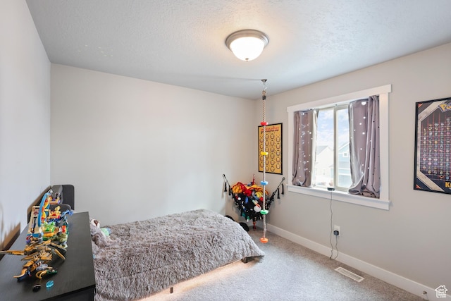 carpeted bedroom featuring baseboards, visible vents, and a textured ceiling