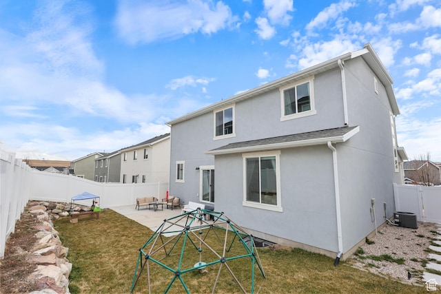 back of house featuring a fenced backyard, a lawn, stucco siding, and a patio area