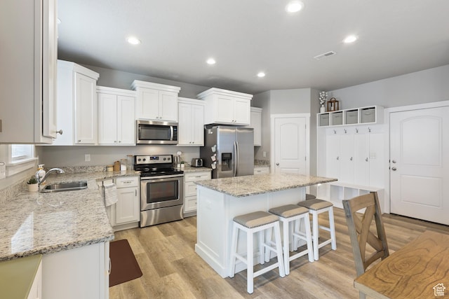 kitchen with a kitchen breakfast bar, light wood-style flooring, a sink, and appliances with stainless steel finishes