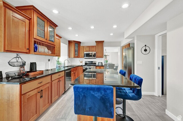 4216 N Wolf Creek Dr, Eden, UT 84310 - kitchen with a breakfast bar area, stainless steel appliances, dark stone counters, a kitchen island, and a sink