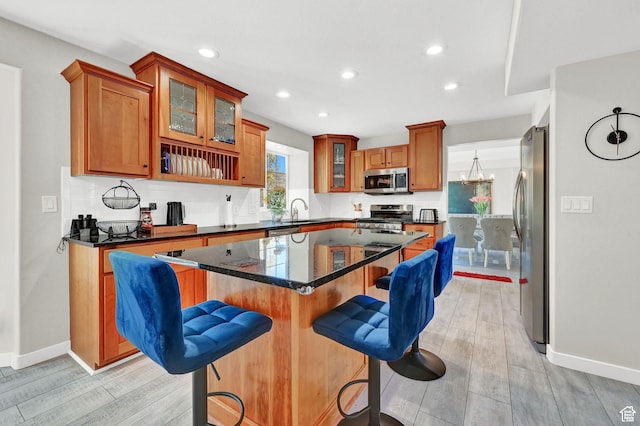 4216 N Wolf Creek Dr, Eden, UT 84310 - kitchen featuring a kitchen breakfast bar, light wood-type flooring, a center island, appliances with stainless steel finishes, and brown cabinetry
