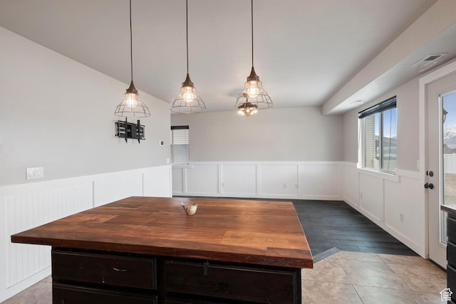 unfurnished dining area featuring a wainscoted wall, a decorative wall, and wood finished floors
