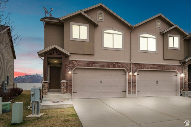 townhome / multi-family property featuring concrete driveway, an attached garage, and stucco siding