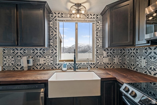 kitchen with wooden counters, appliances with stainless steel finishes, a sink, and decorative backsplash