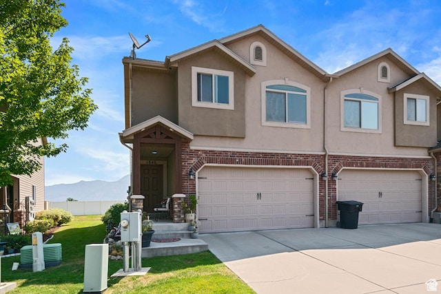 multi unit property featuring concrete driveway, a garage, stucco siding, and a front yard