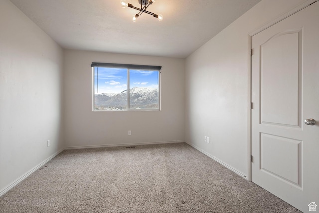 empty room with carpet floors, a chandelier, and baseboards