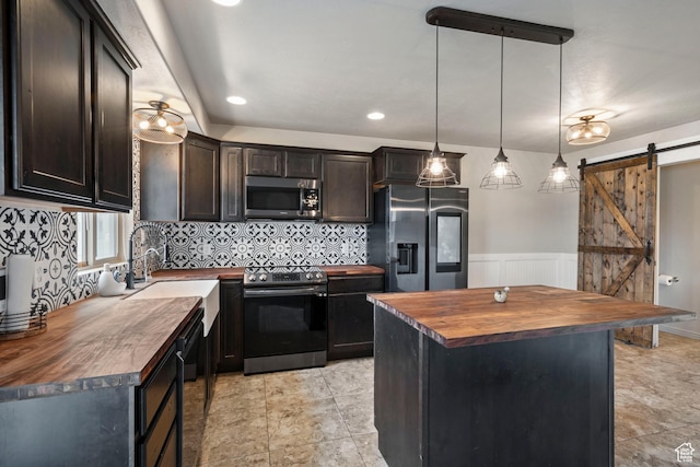 kitchen with butcher block counters, appliances with stainless steel finishes, a barn door, decorative backsplash, and dark brown cabinetry
