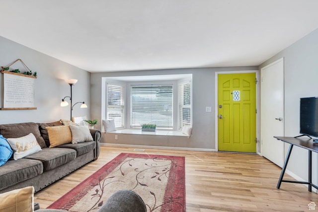 living area with visible vents, baseboards, and wood finished floors