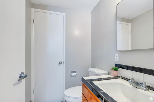 half bathroom with toilet, vanity, and tasteful backsplash