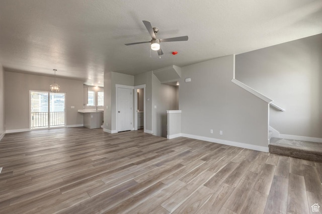 2746 E 1060 S, Spanish Fork, UT 84660 - unfurnished living room featuring baseboards, wood finished floors, stairway, and ceiling fan with notable chandelier