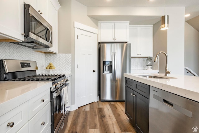 2748 E 1060 S, Spanish Fork, UT 84660 - kitchen with white cabinetry, stainless steel appliances, decorative backsplash, a sink, and wood finished floors