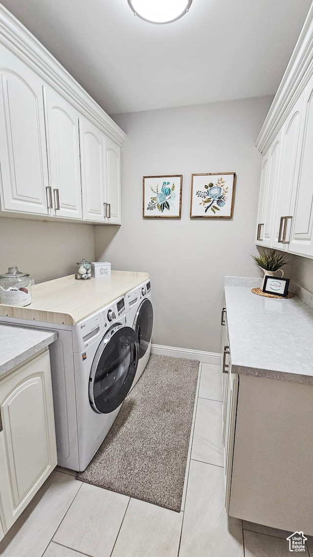 laundry room with light tile patterned flooring, independent washer and dryer, cabinet space, and baseboards