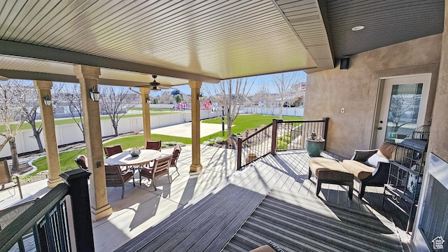 wooden terrace with ceiling fan, a fenced backyard, outdoor dining space, a lawn, and a patio area