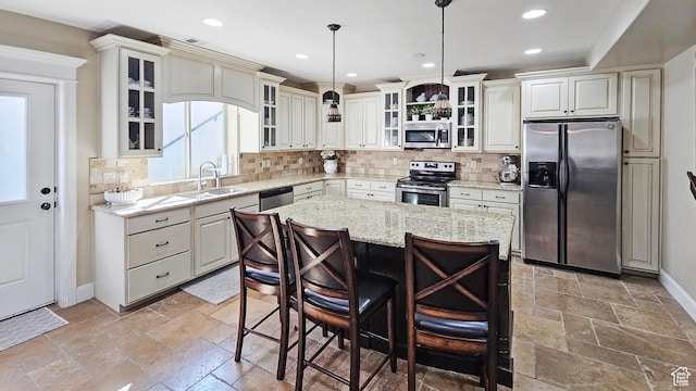 kitchen featuring a sink, stainless steel appliances, backsplash, and stone tile flooring