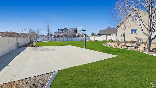 view of sport court featuring a fenced backyard, basketball court, and a yard