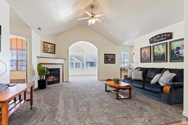 living area featuring carpet flooring, a tile fireplace, plenty of natural light, a ceiling fan, and lofted ceiling