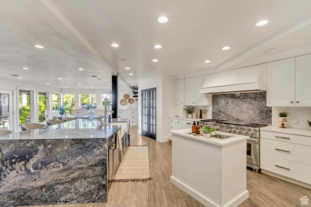 1448 E 155 S, Lindon, UT 84042 - kitchen featuring high end stainless steel range, an island with sink, custom range hood, and decorative backsplash