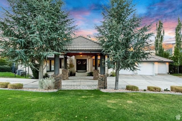 view of front of property featuring concrete driveway, stucco siding, fence, a tiled roof, and a front lawn