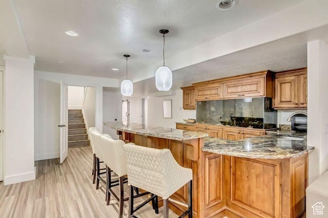 1448 E 155 S, Lindon, UT 84042 - kitchen with a breakfast bar, a sink, light wood-style floors, pendant lighting, and light stone countertops