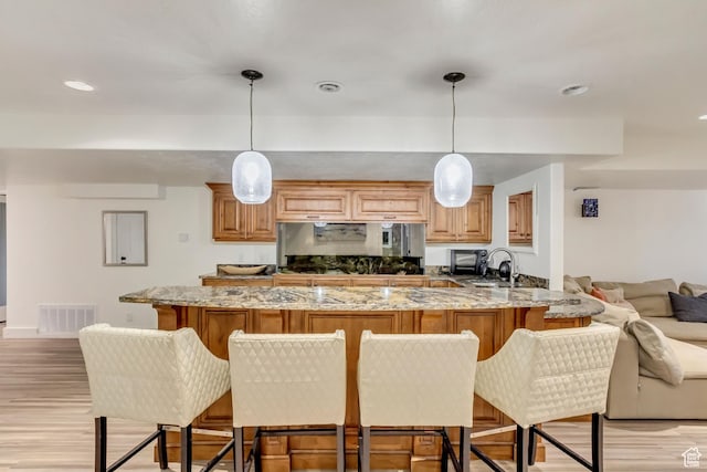 1448 E 155 S, Lindon, UT 84042 - kitchen featuring light stone counters, a sink, light wood finished floors, a kitchen bar, and visible vents