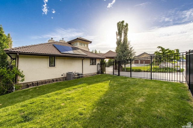 1448 E 155 S, Lindon, UT 84042 - rear view of house with a chimney, cooling unit, fence, roof mounted solar panels, and a yard