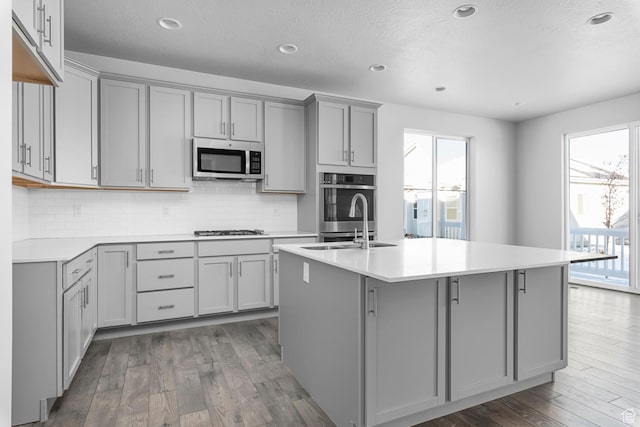 kitchen with gray cabinets, a sink, stainless steel appliances, and wood finished floors