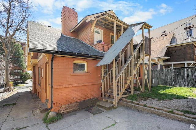 427 E 1st Ave, Salt Lake City, UT 84103 - back of property featuring stairway, roof with shingles, a chimney, fence, and brick siding